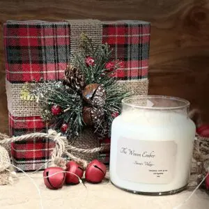 A candle sitting on top of a table next to some christmas decorations.